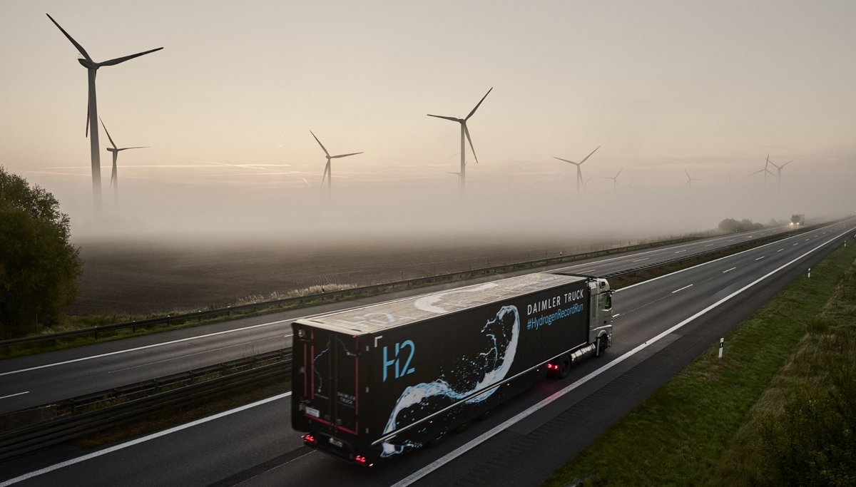 GenH2 truck drives over the road, wind turbines can be seen in the background