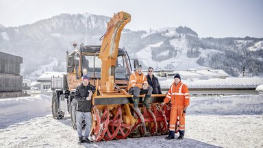 Vier Mann im Schnee und ihr Unimog