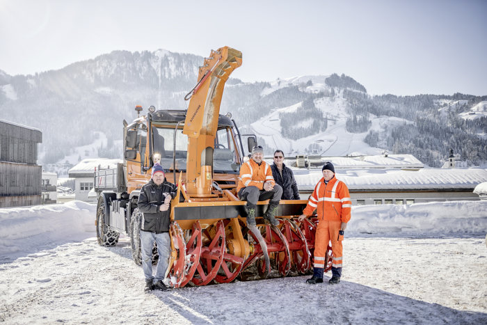 Vier Mann im Schnee und ihr Unimog