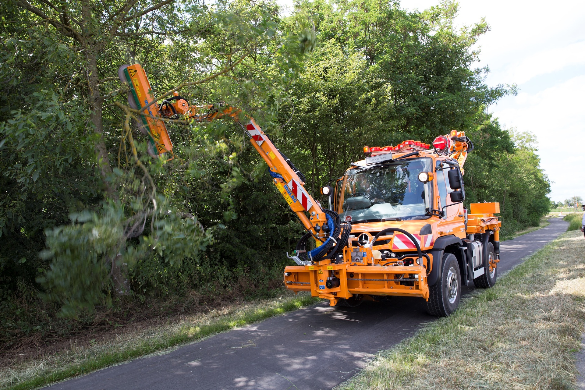 Unimog implement carrier with front mower, hedge trimmer, and spreader The Unimog for modern agriculture: three implement carriers at Agritechnica