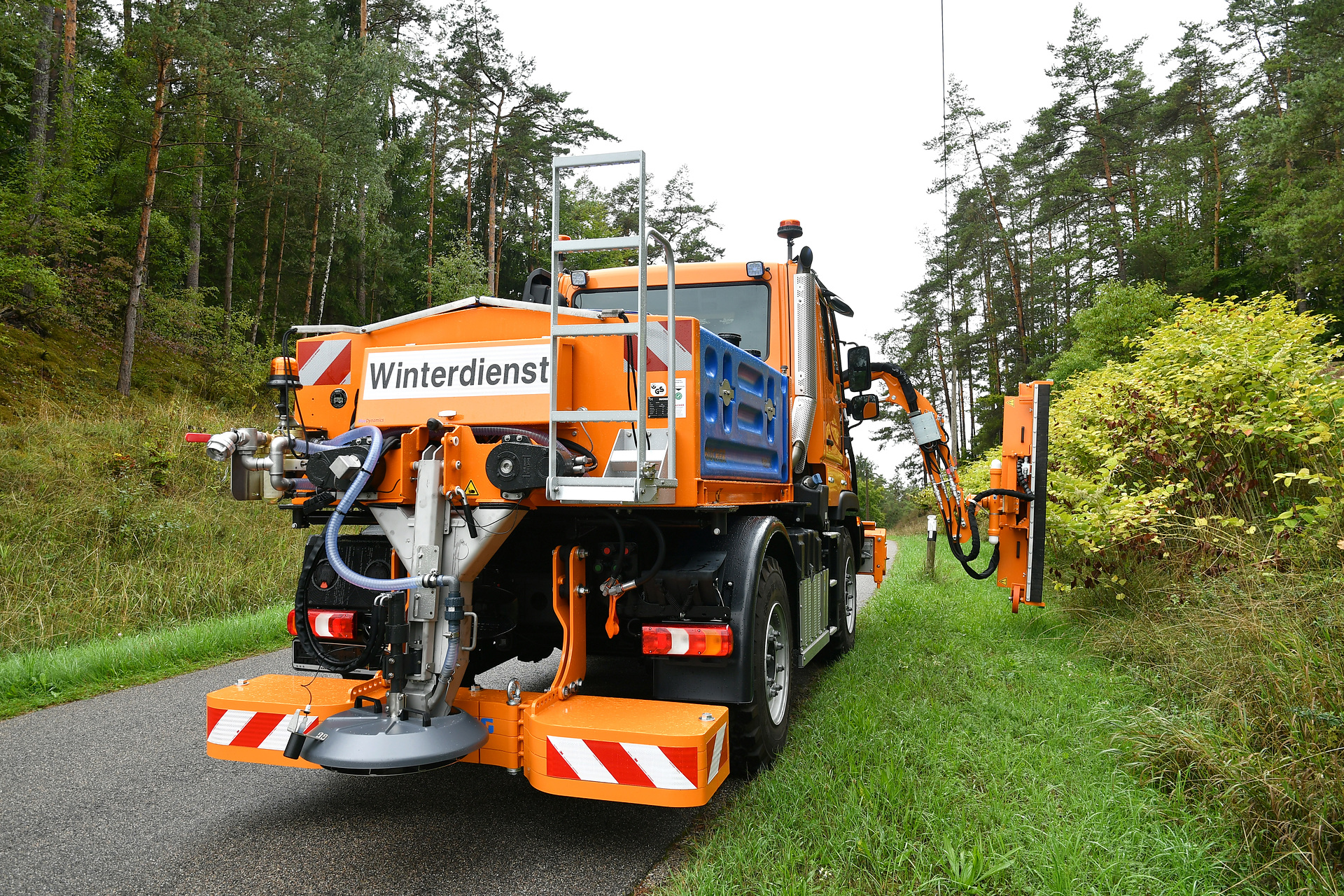 Unimog implement carrier with front mower, hedge trimmer, and spreader The Unimog for modern agriculture: three implement carriers at Agritechnica